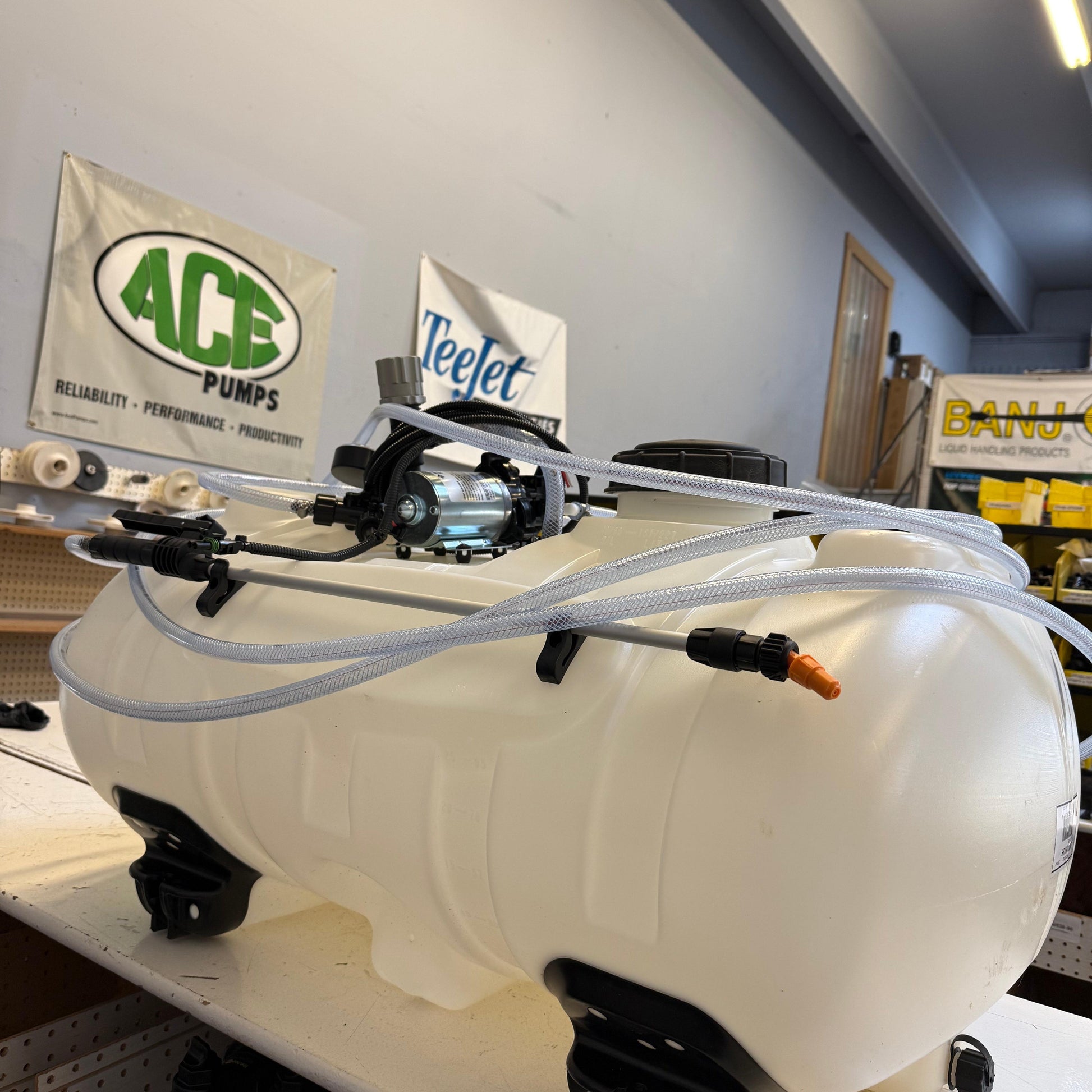 40-gallon white plastic ATV sprayer tank with a 3GPM pump, clear hoses, and a spray wand mounted on top.