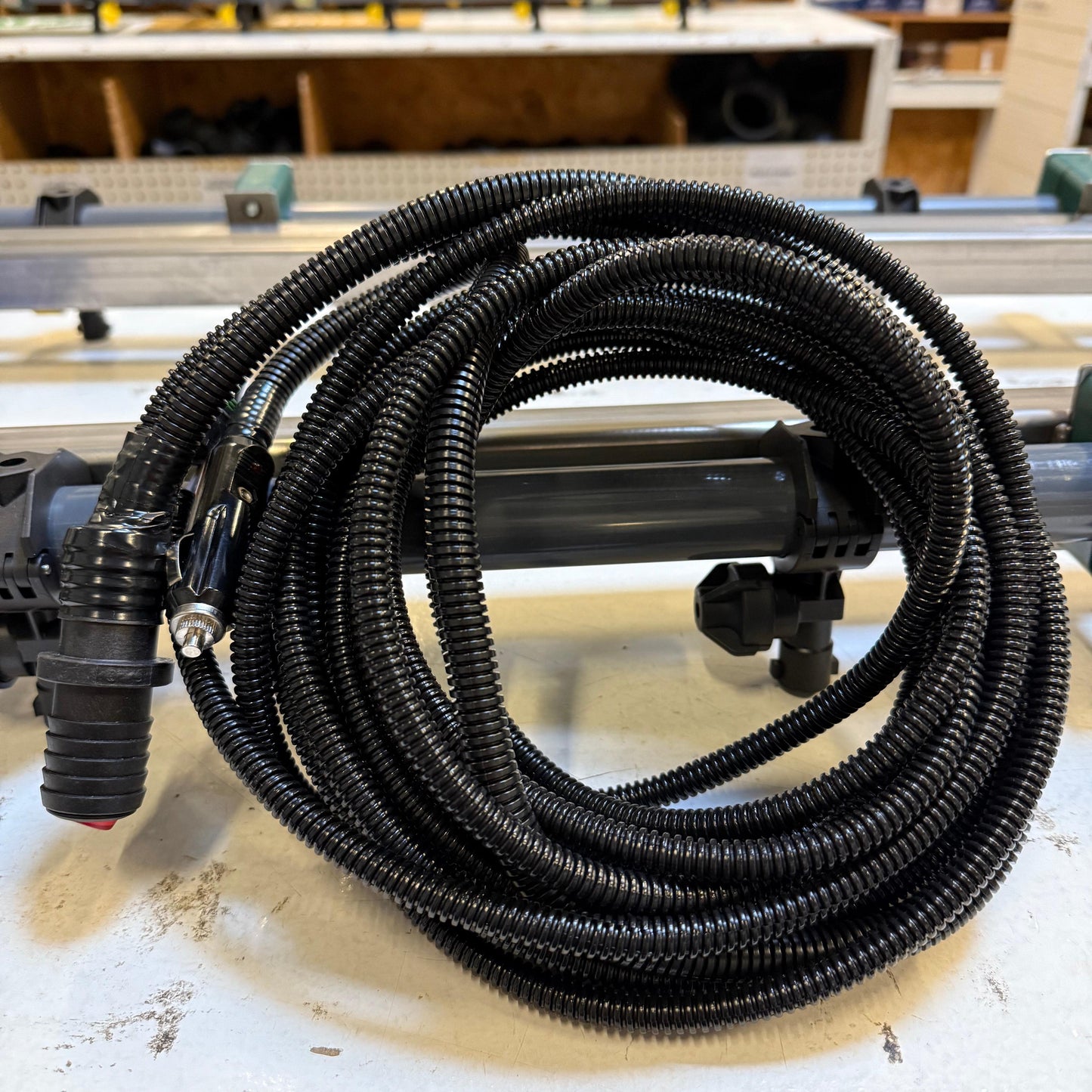 Coiled black electrical wire encased in protective corrugated plastic tubing with a single switch connector.