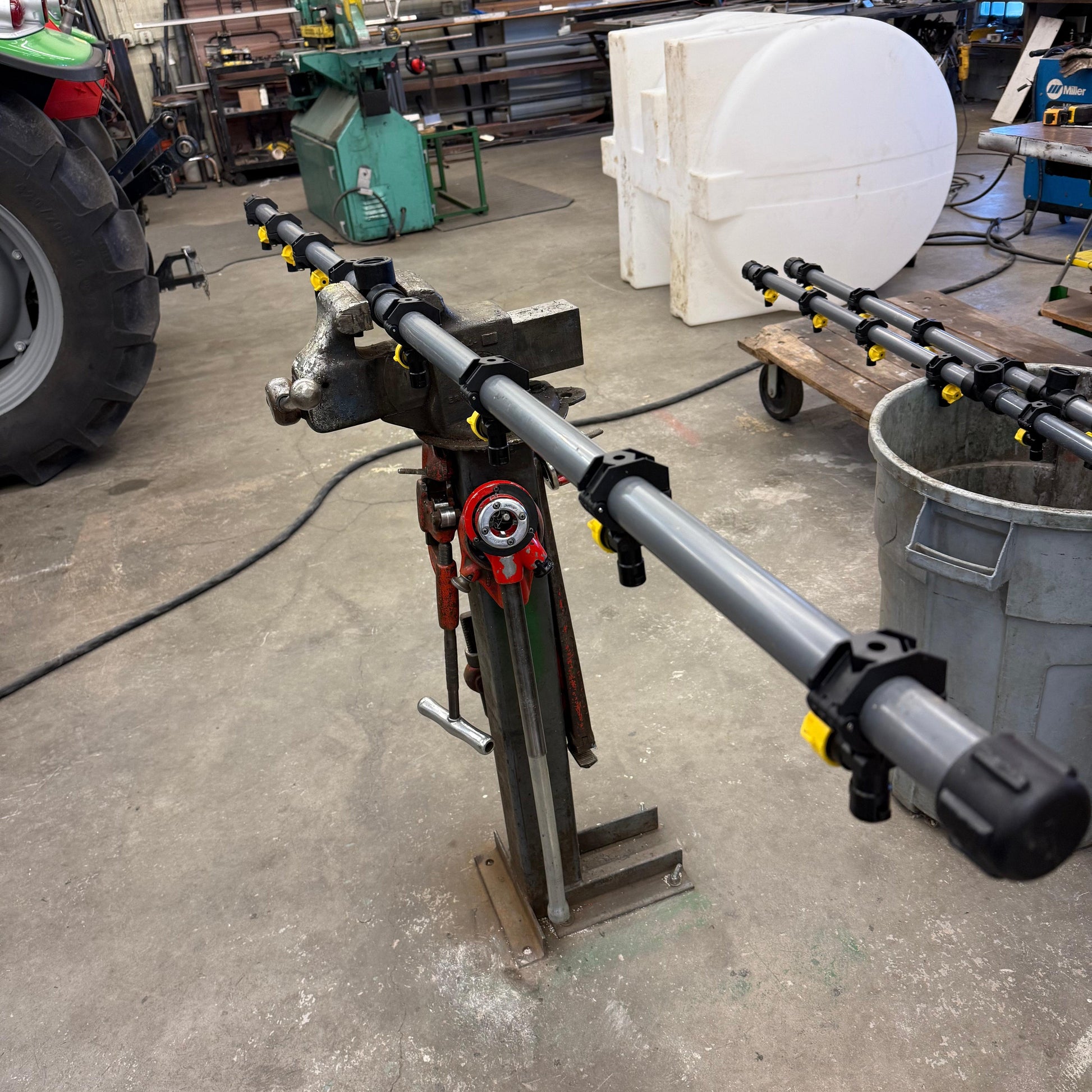 Grey single lane de-ice boom featuring black spray tip mounts, secured in a metal workshop vise.